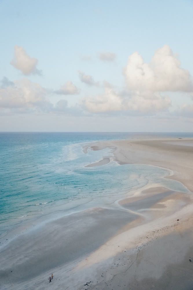 Overhead perspective capturing peaceful blue waters merging with pristine white sandy beaches and soft ripples