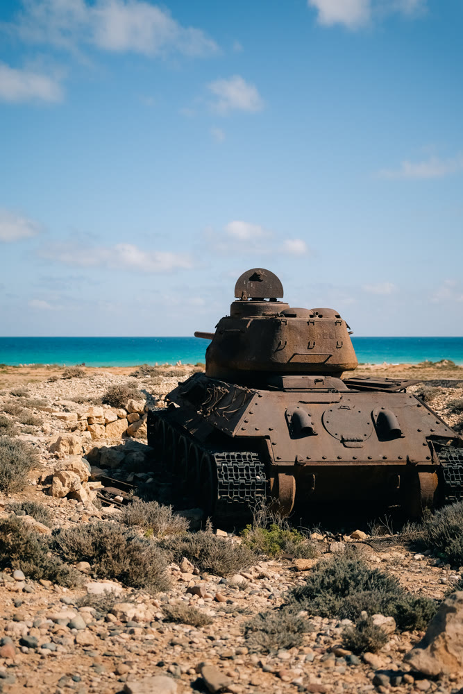 Old ship remains. Weathered abandoned armored vehicle lies amid limestone formations under vivid sky
