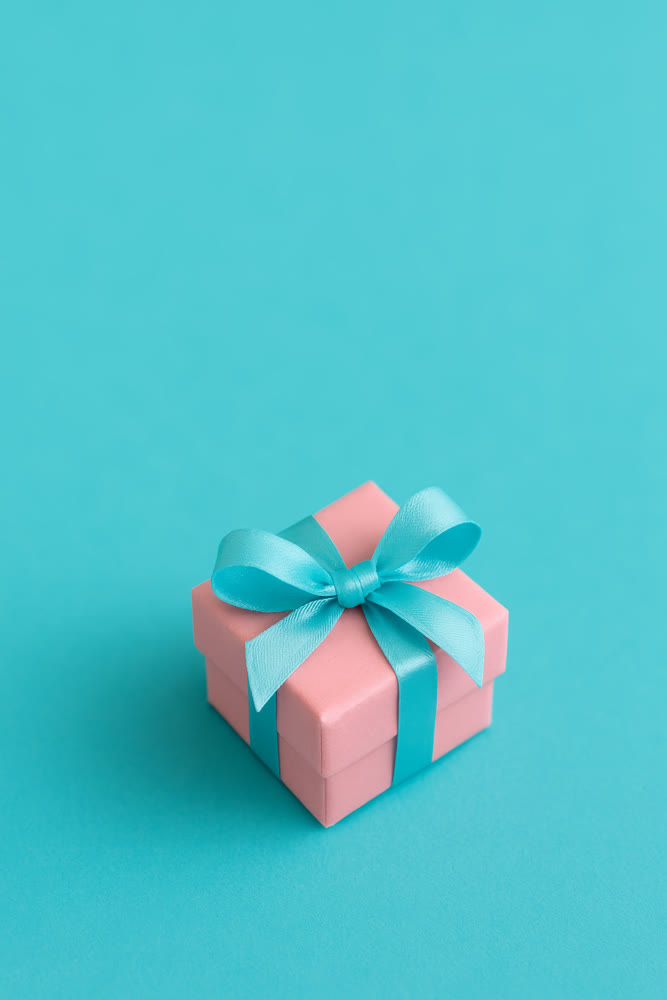 Stylish pink box adorned with turquoise ribbon. Chic gift box decorated with satin bow and soft lighting