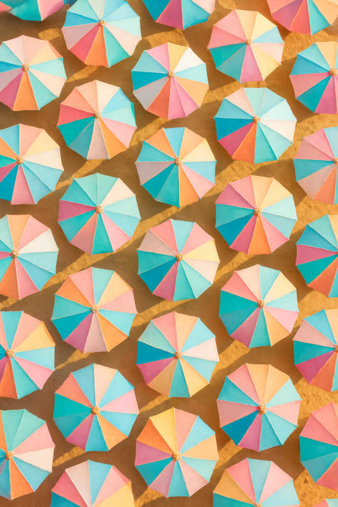 High aerial perspective showcasing vivid umbrellas forming structured patterns on sandy surface