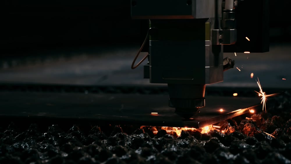 Industrial laser process. Molten droplets illuminate textured surface during intense metal cutting