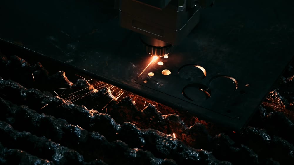 Metal laser pierces through thick plate. Hot glowing laser forms circular metal holes with sparks