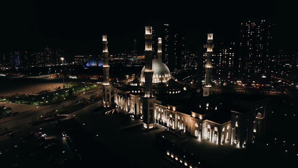Nighttime city view showcasing luminous mosque domes surrounded by sleek skyscrapers and peaceful streets
