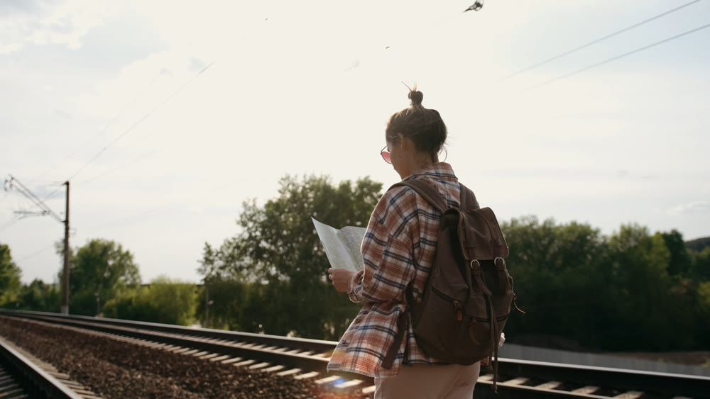Explorer studies map at sunset. Person with backpack gazes at distant horizon in calm countryside atmosphere