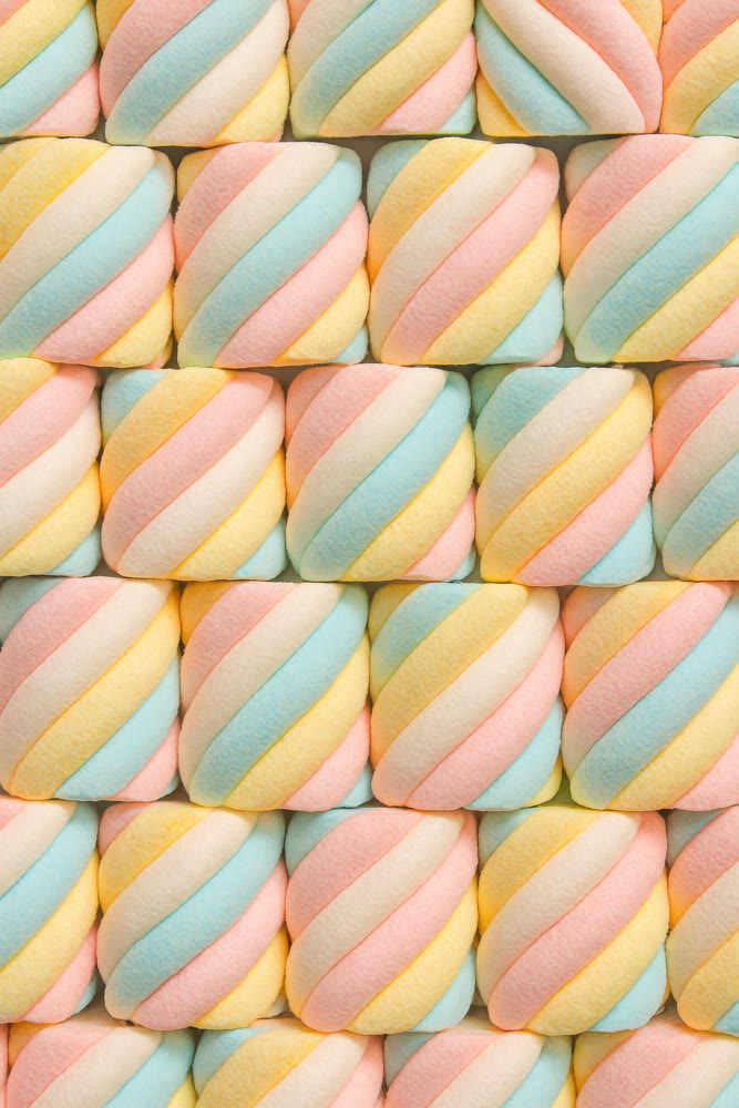 Bright pastel confections arranged precisely. Decorative marshmallow designs in organized diagonal layout